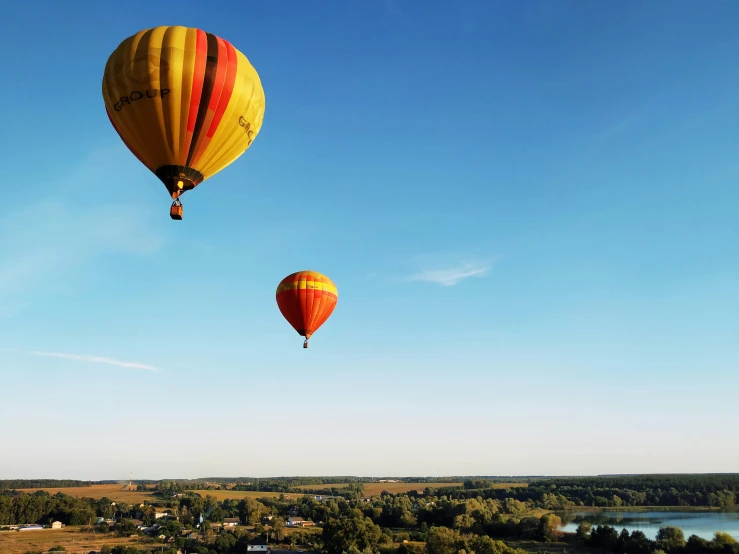 two  air balloons flying in a bright blue sky over trees