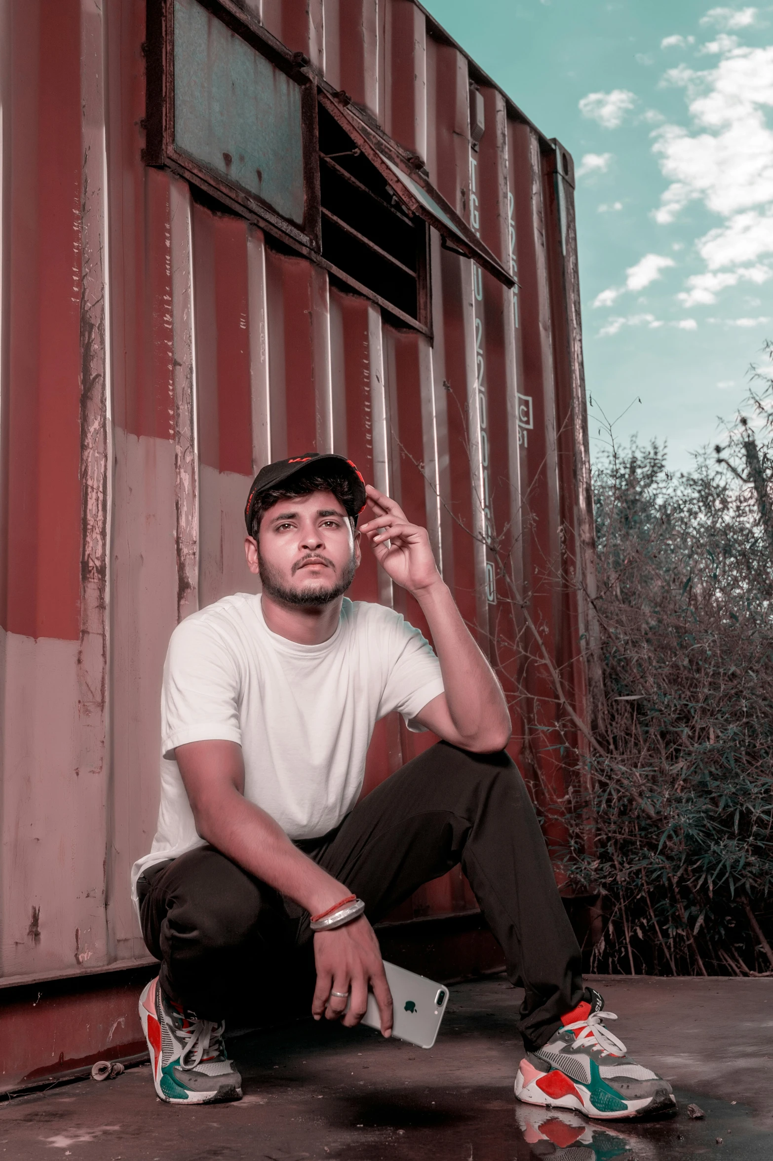 man crouching in front of a corrugated building with his skateboard