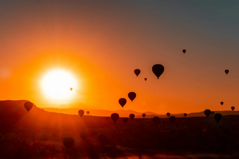 a group of balloons flying into the sunset