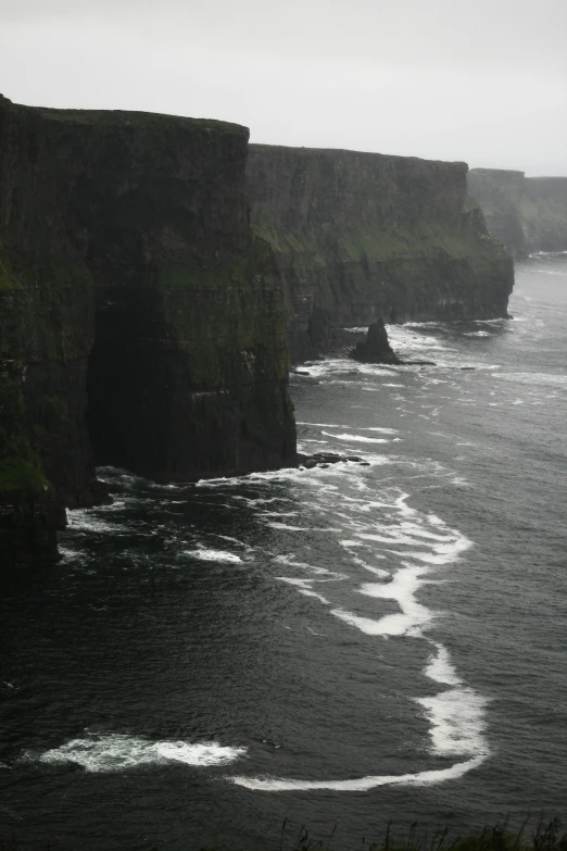 cliffs in the ocean with a long distance view of the cliff, beach and water