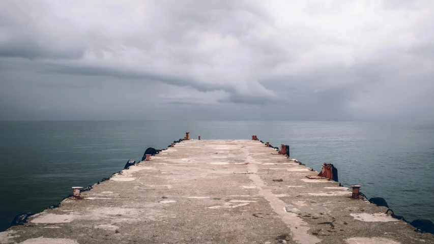 a woman and child sitting on the edge of a pier near a body of water