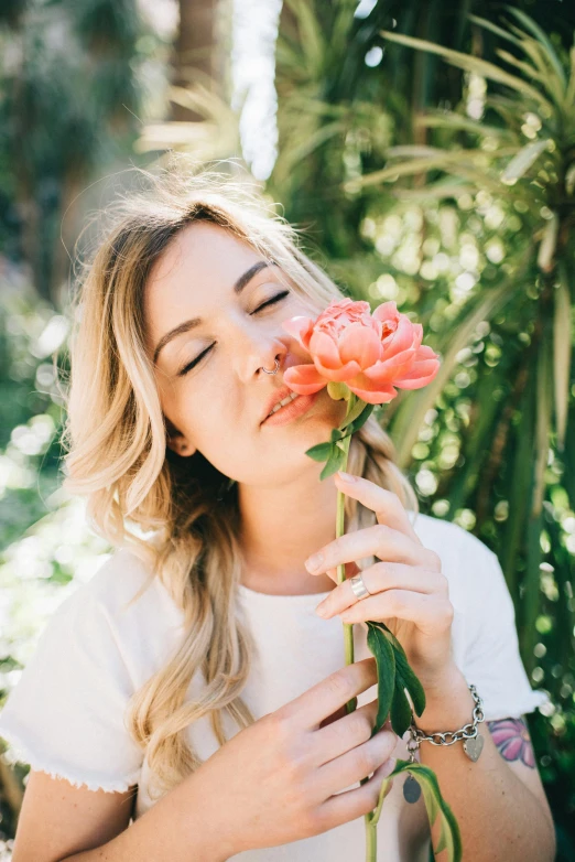 a woman smelling a flower while it is blooming