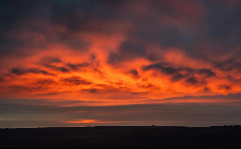 the sun sets over a small group of hills