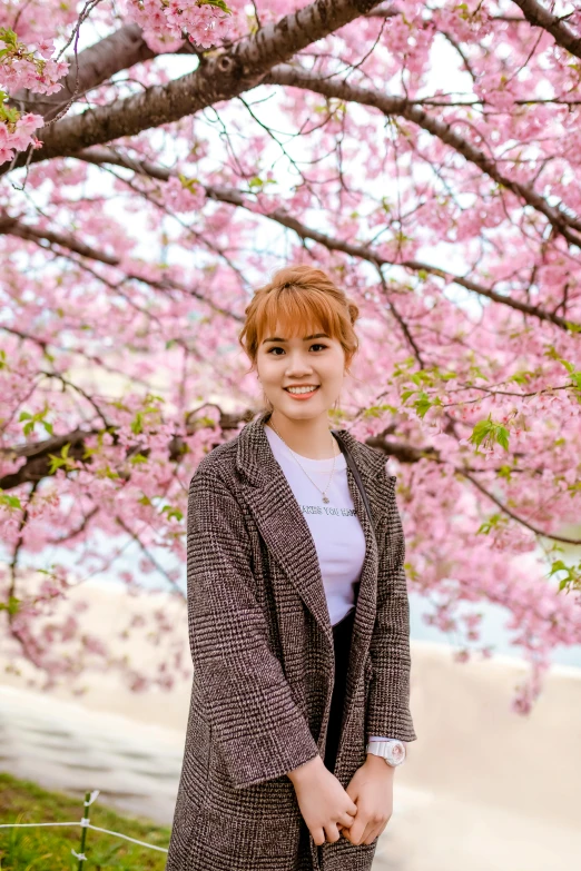 a woman standing in front of a cherry blossom tree