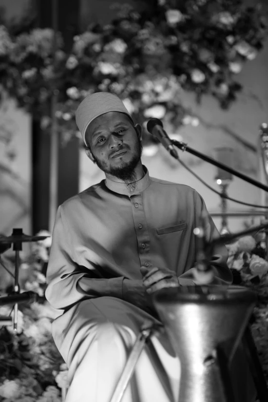 black and white image of a man sitting at a table with a drum