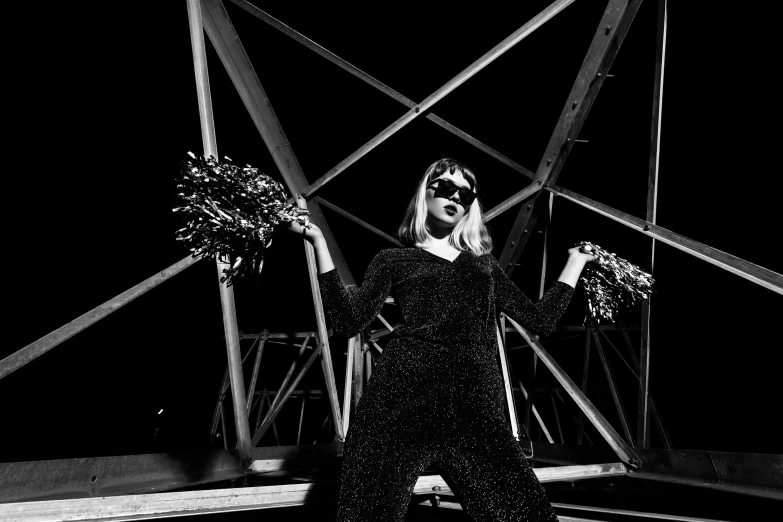 a woman wearing sunglasses standing on top of a metal bridge