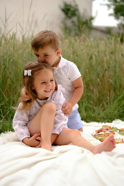 two children are on a blanket in the grass