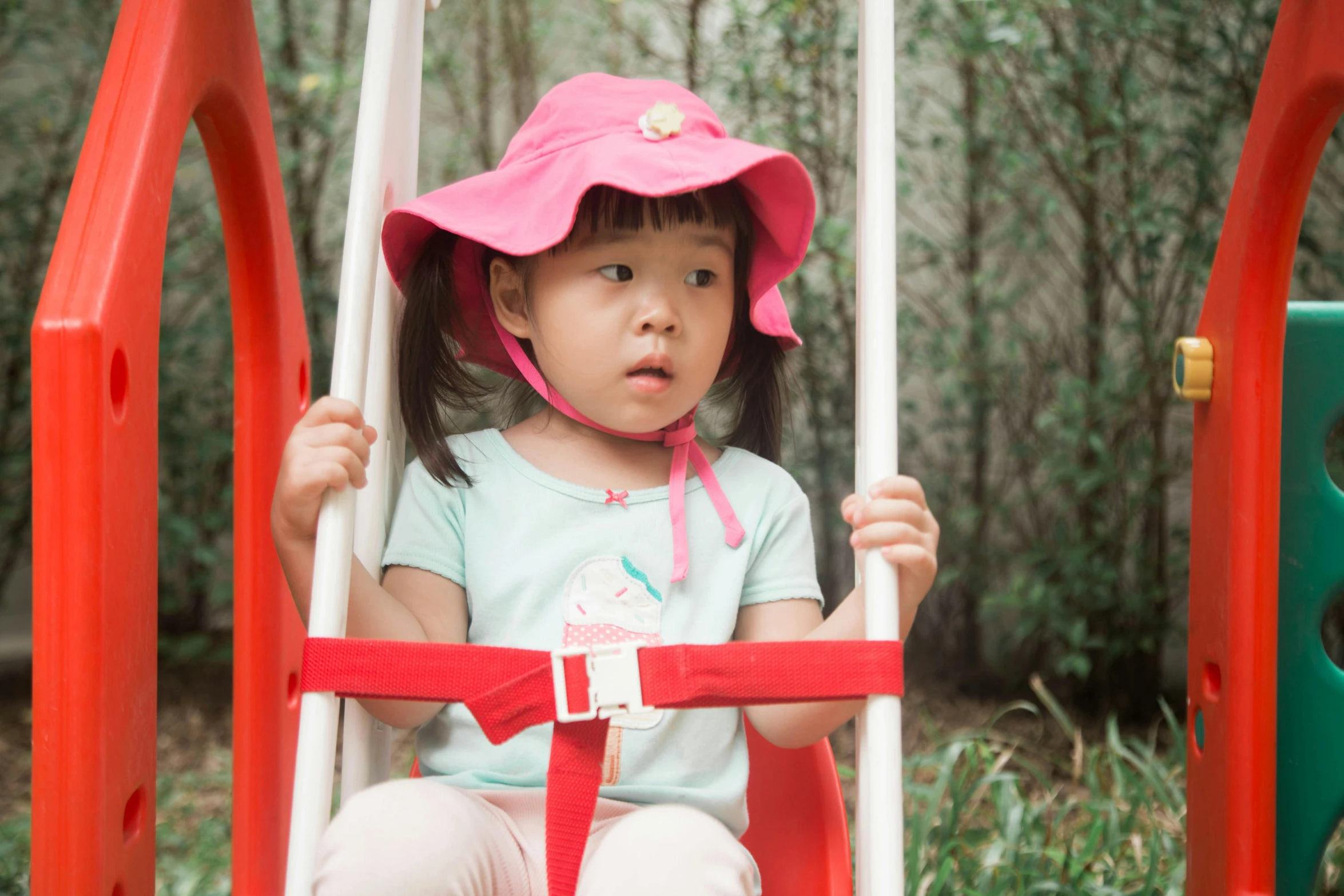 small girl on swing with red and white poles