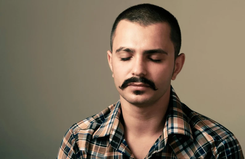 a man in checkered shirt looking down with a frown