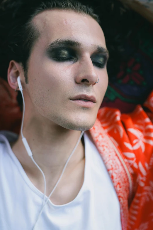 a young man wearing black and silver looks at the camera