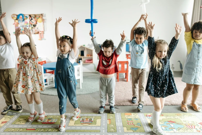 several children in a room with their arms up