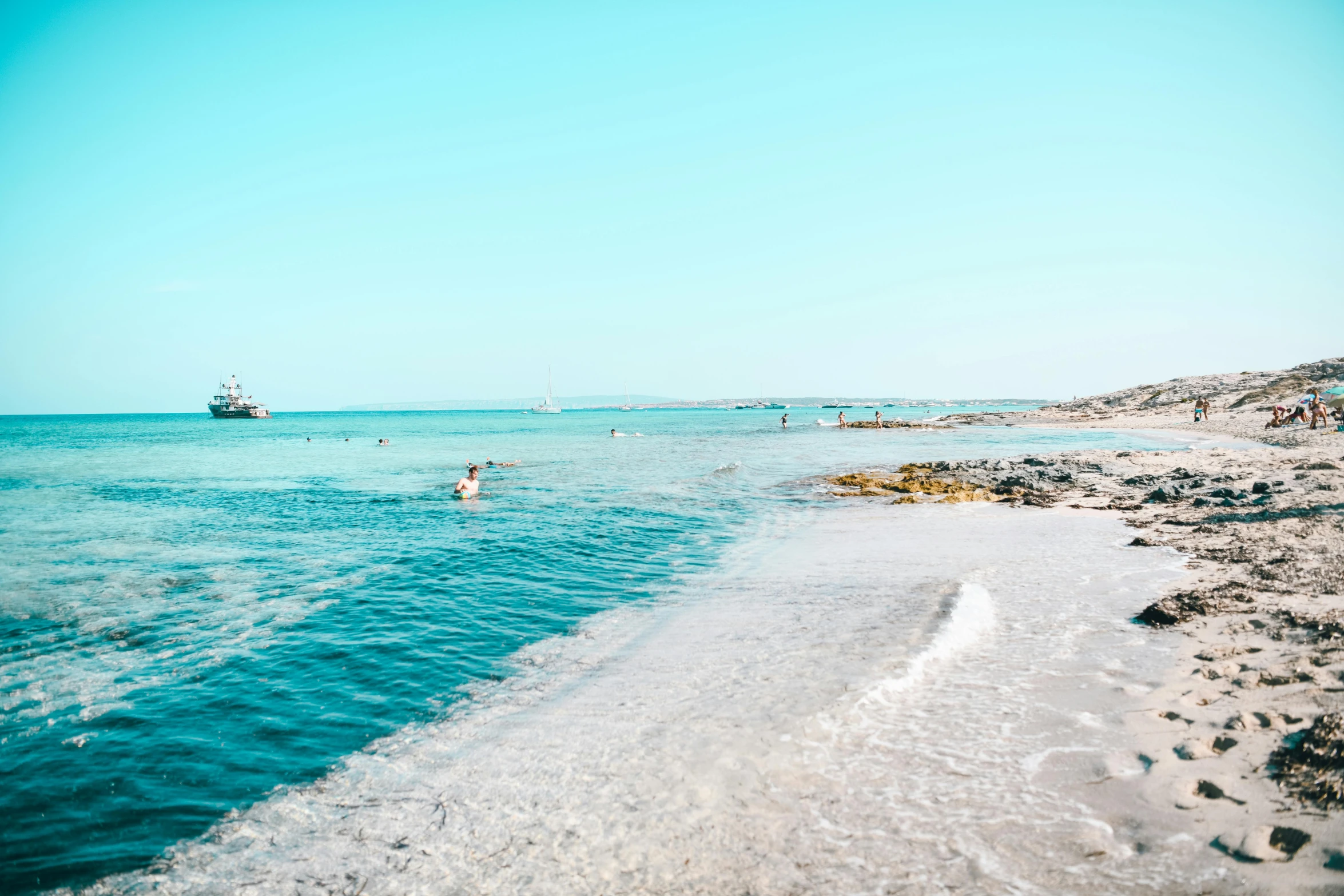 a beach with a body of water and a boat on the shore