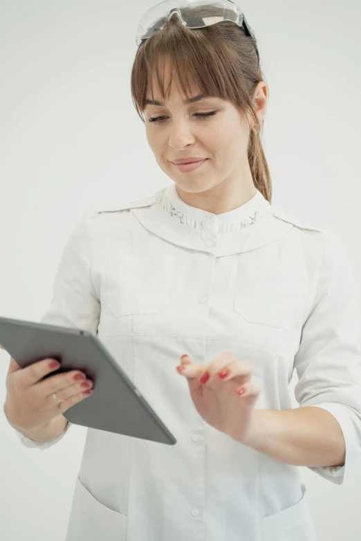 a woman wearing a white top looking at a small tablet