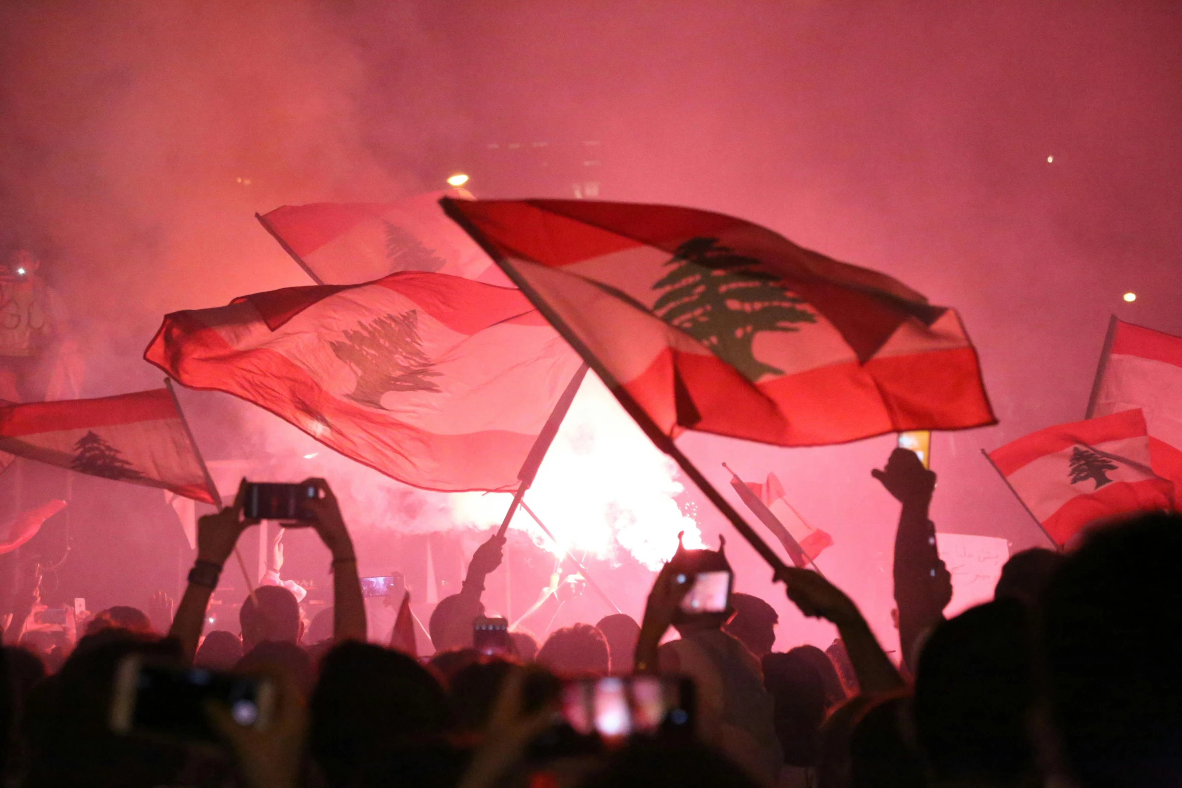 people waving flags at the same time with their cell phones