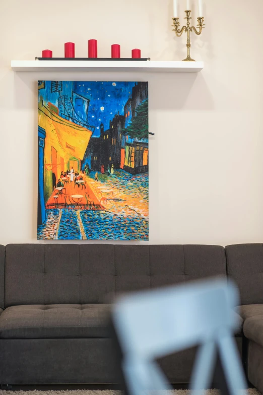 a modern couch and blue glass table with candle holders on the ledge