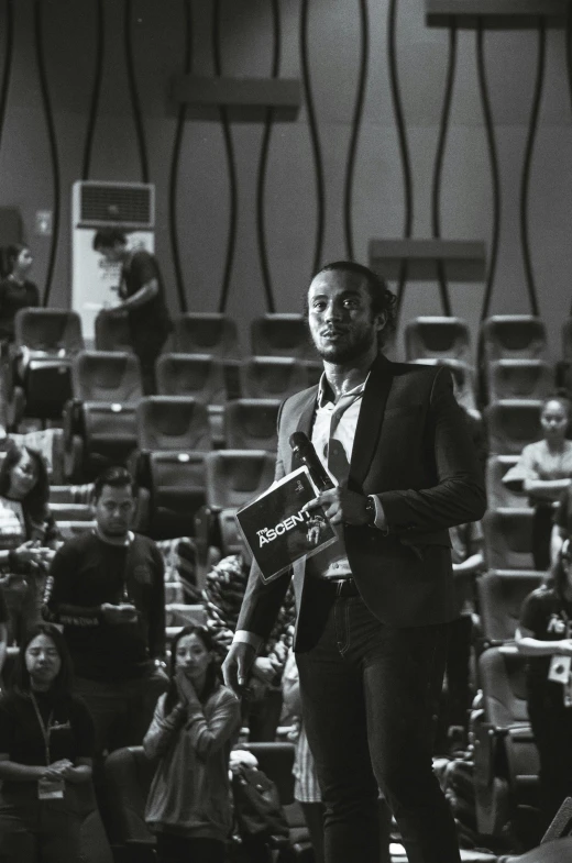 a black man is standing and speaking at a conference