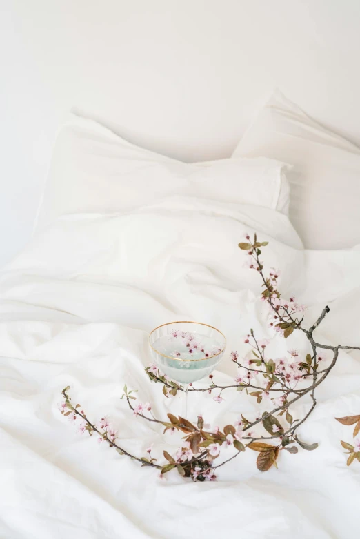 white bed covered with soft sheets and a tea cup on top