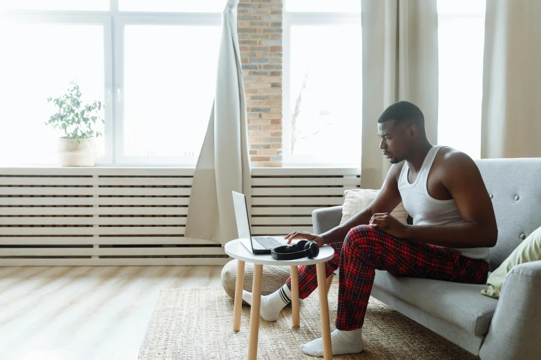 a man wearing red and black checkered pajamas is on a couch