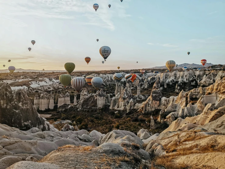 some  air balloons are flying in the sky over a rock landscape