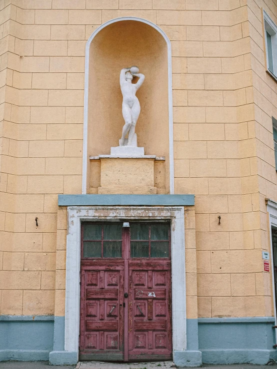 the side of a building with a doorway and a statue on top