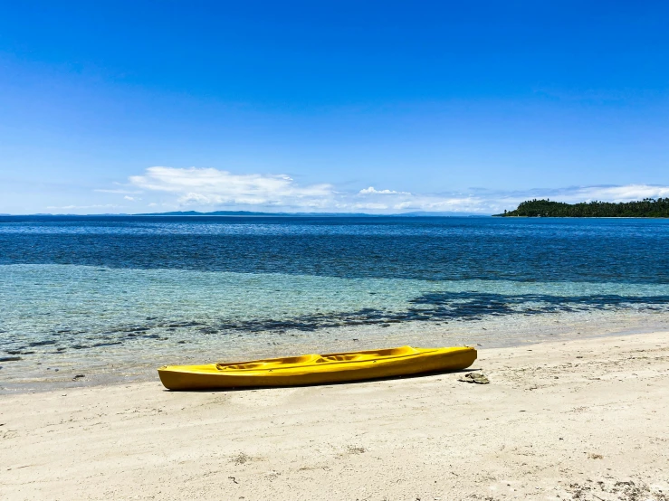 a yellow canoe sitting on top of a sandy beach