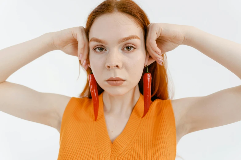 a young lady posing with a red pair of earrings on her ears