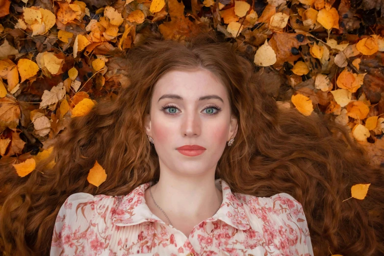 a beautiful young lady posing in front of autumn leaves