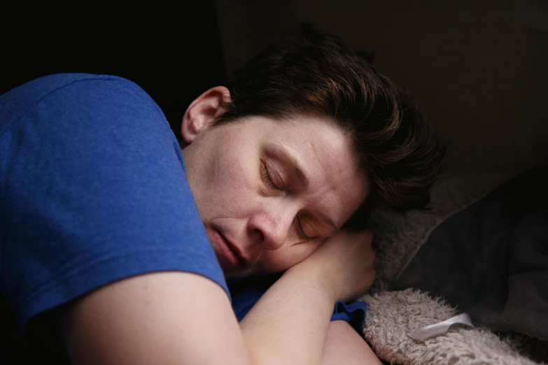 a person sleeping on a bed with his arm over his head