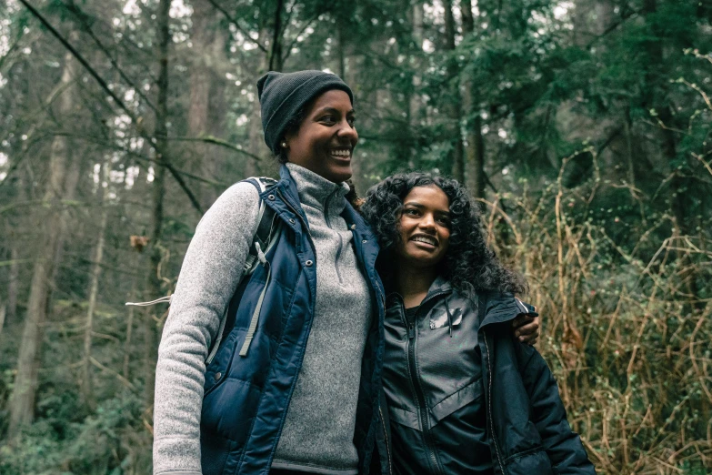 a man and woman pose together in the woods