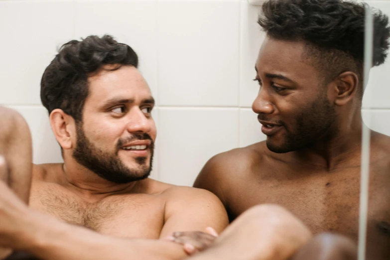 two males are seated in the bathroom mirror