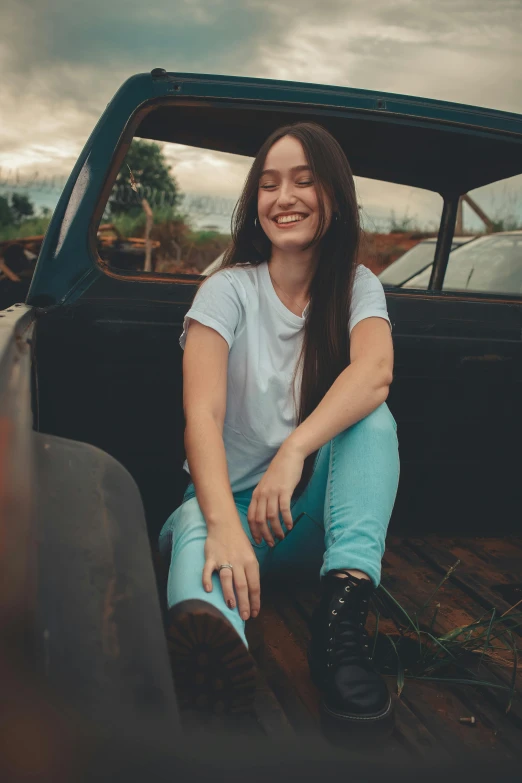 woman with long hair sitting in back of truck and smiling