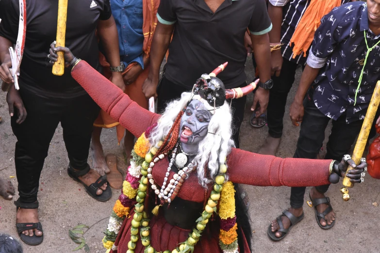 a costumed woman dressed in red and orange holding sticks