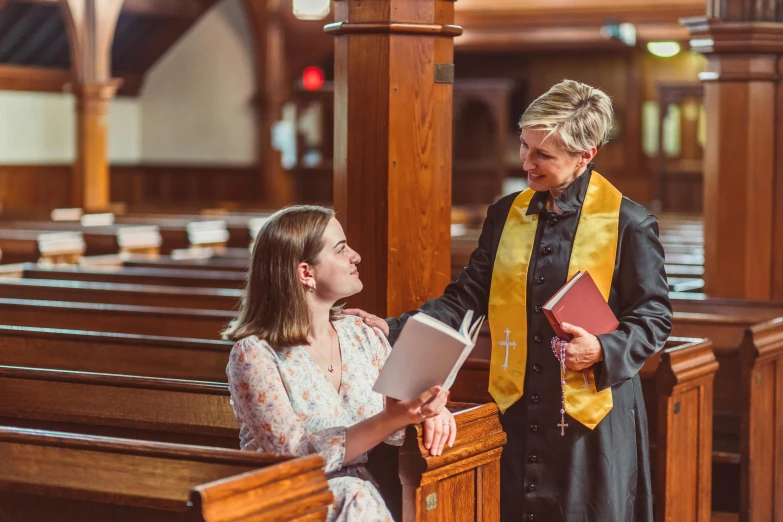 two girls with their hands in each other's pockets, one holding a bible while the other holds her folder