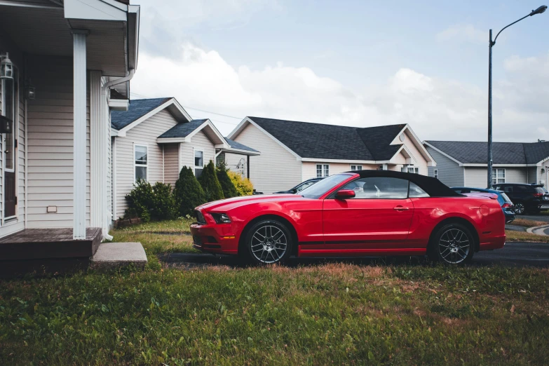 a red mustang parked in front of some houses