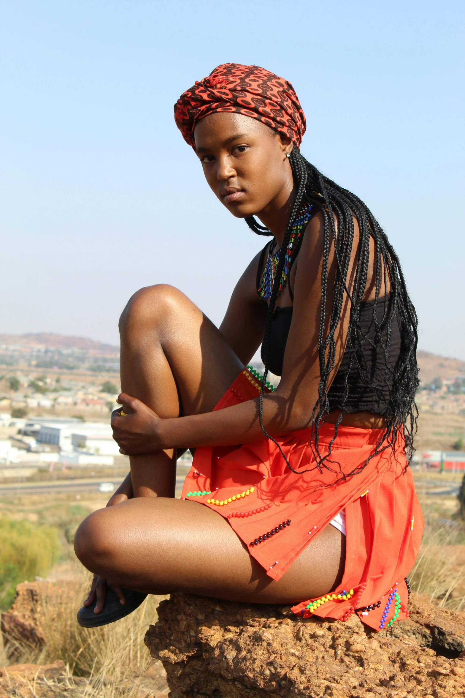 a young black woman sitting on top of a rock