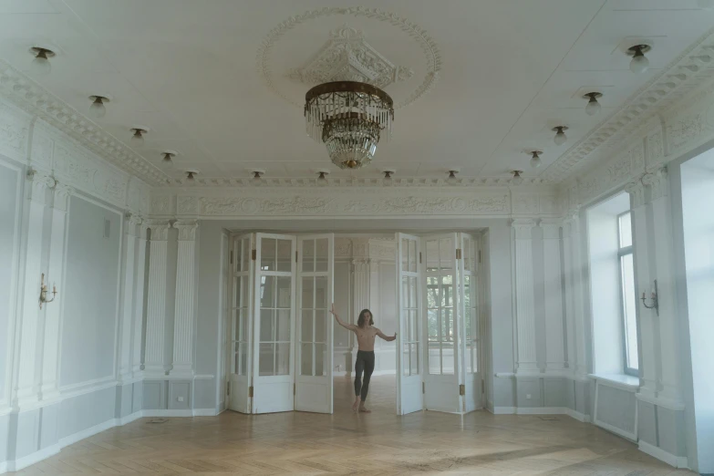 a woman standing in an empty room with a chandelier