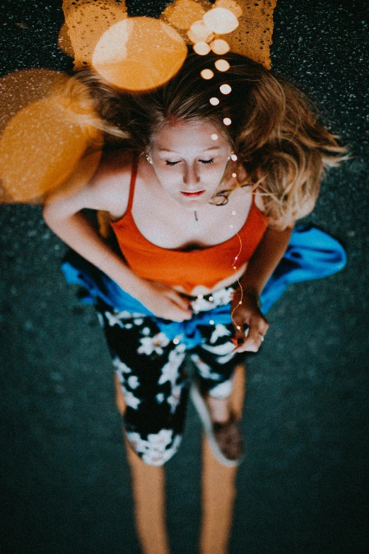 woman in orange top looking down with lots of balloons on her head