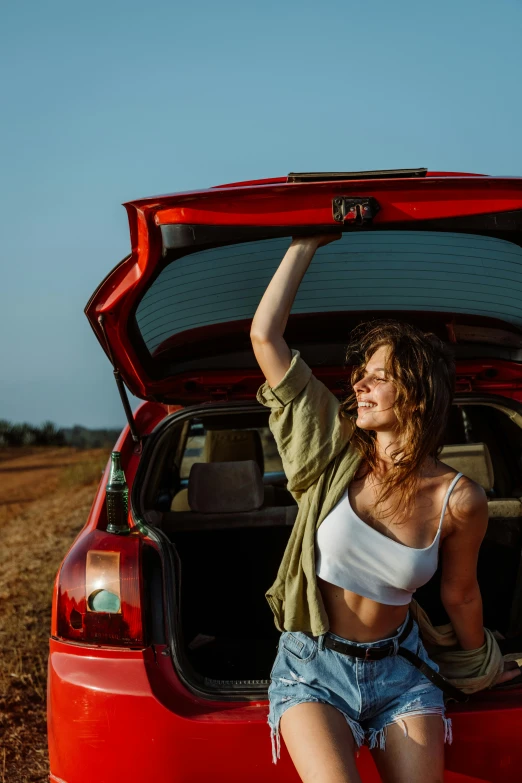 a woman sitting in the boot of a red car