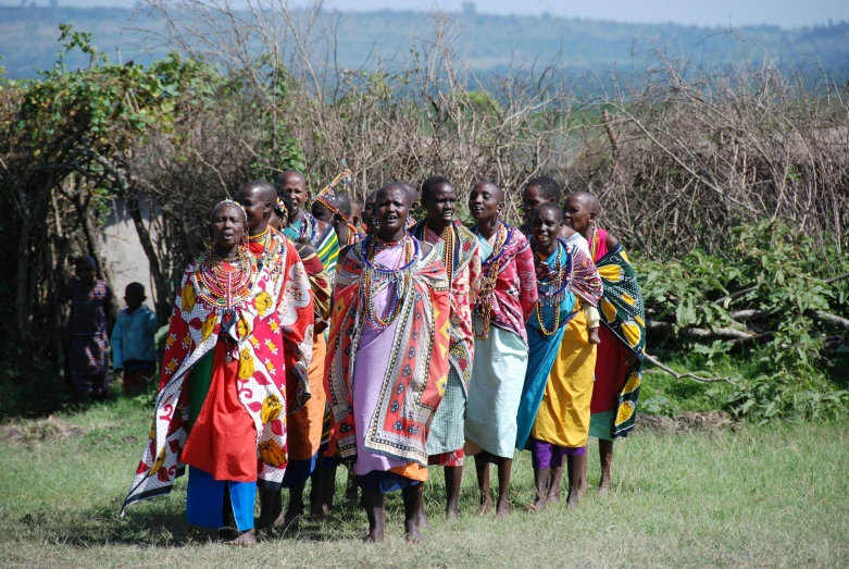 many people standing together on a field near some bushes