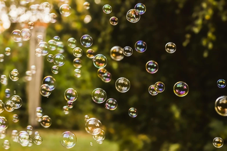 bubbles are flying in the air beside trees