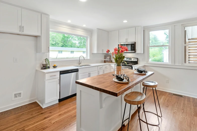 an empty kitchen with hardwood floors, white cabinetry and counter tops