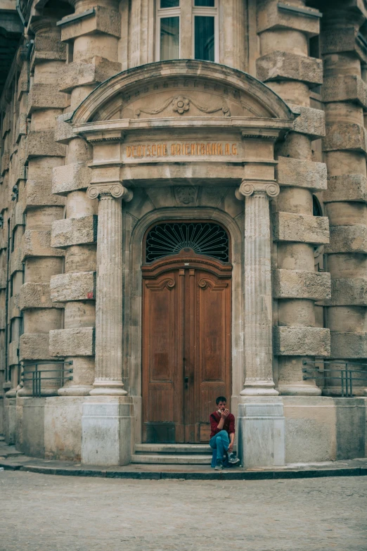 two people sit outside of an old building with a wooden door