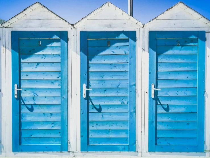 three blue shuttered buildings with a cross on top