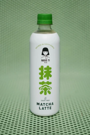 a green bottle on a green surface with a girl and japanese characters in it