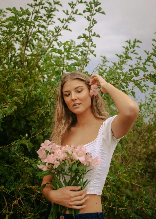 a woman in shorts and a crop top with her arms above her head holding a flower