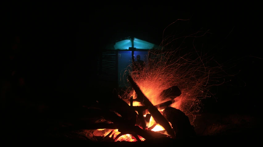 some fire is lit in the dark while a building is lit up