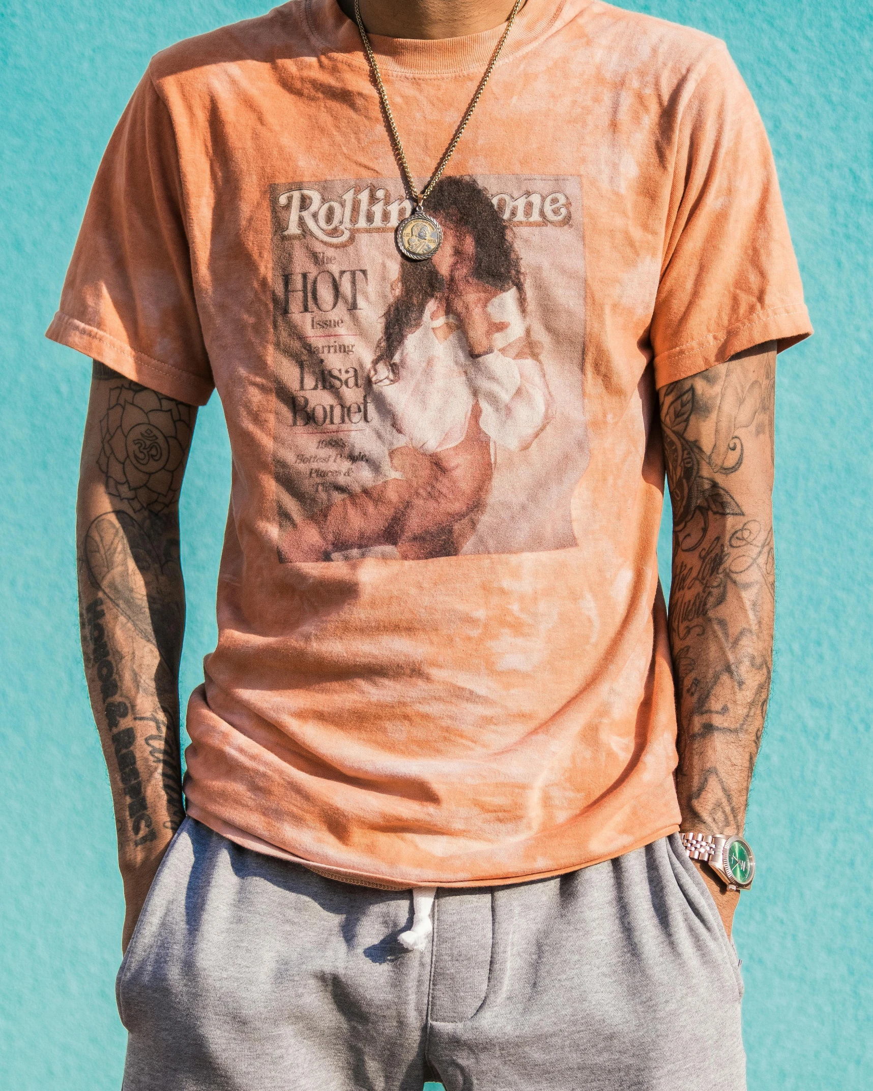 a man with a tattoo wearing shorts and an orange shirt