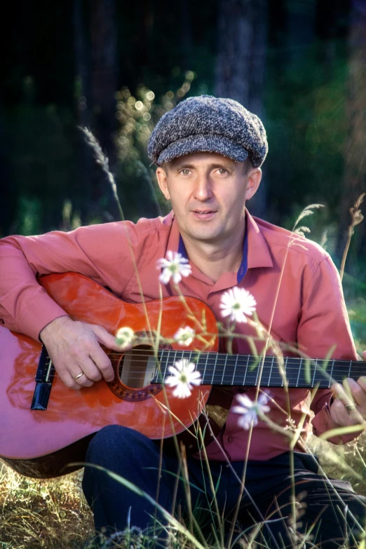 a man with a hat holding an acoustic guitar