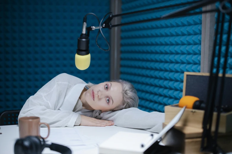 an older woman lays head down on a table while staring at the camera