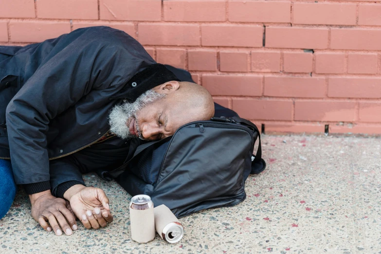 an old man wearing a jacket laying down and looking at his hand